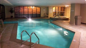 Une piscine intérieure à l’eau claire, entourée de murs carrelés et dotée d’un plafond laissant apparaître les conduits.