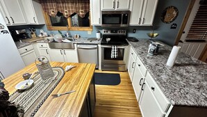 A kitchen with white cabinets, a granite countertop, a wooden dining table, and a stainless steel oven. - Tennessee's Finest Smoky Mountain Vacation Rental Getaway!  (Townsend)