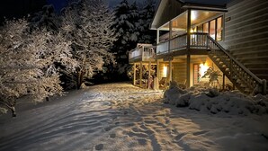 A two-story wooden cabin with a balcony, surrounded by snow-covered trees. - Tennessee's Finest Smoky Mountain Vacation Rental Getaway!  (Townsend)