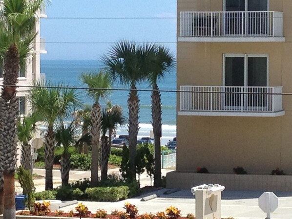 A multi-story building with balconies overlooking a beach.