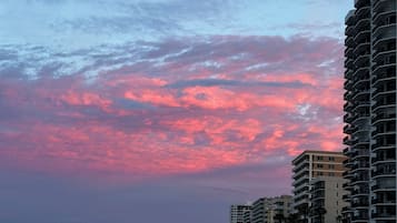 Une plage avec de grands immeubles en arrière-plan et un ciel au coucher du soleil.