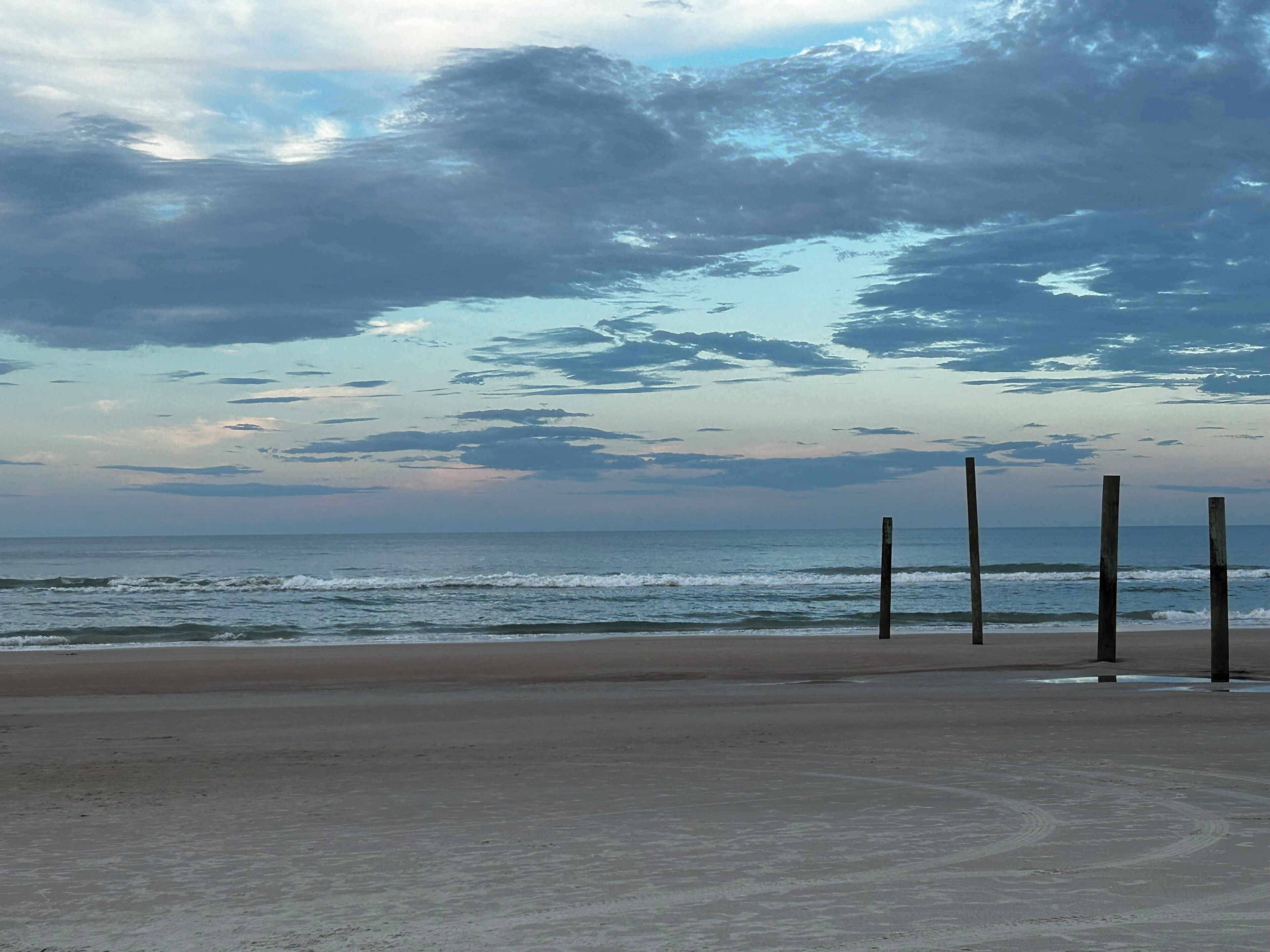 A beach with a sandy shore and wooden posts.