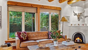 A cozy living room with a leather sofa, a rustic coffee table, and a fireplace.