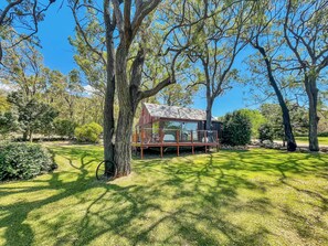 Escape to a serene cabin surrounded by lush greenery and mature trees, with a spacious deck for taking in the natural beauty.