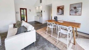A modern living space with a dining area, white furniture, and artwork on the walls.