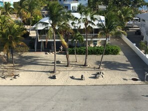 A beachfront property with a two-story building, palm trees, and a sandy beach. - Open Water views, 80' dock Private Pool Ice machine DIRECT ACCESS  open water (Marathon)