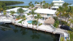 A marina with boats docked, a swimming pool, and a thatched-roof structure. - Open Water views, 80' dock Private Pool Ice machine DIRECT ACCESS  open water (Marathon)