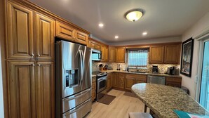 A modern kitchen with wooden cabinets, stainless steel appliances, and a granite countertop. - Open Water views, 80' dock Private Pool Ice machine DIRECT ACCESS  open water (Marathon)