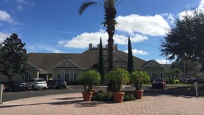 A residential area with a paved driveway, parked cars, and a row of houses with a central palm tree. - 25 minutes to Disney World! Family-sized townhouse (Kissimmee)