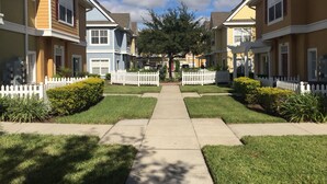 A row of townhouses with a central walkway, white picket fences, and well-maintained lawns. - 25 minutes to Disney World! Family-sized townhouse (Kissimmee)