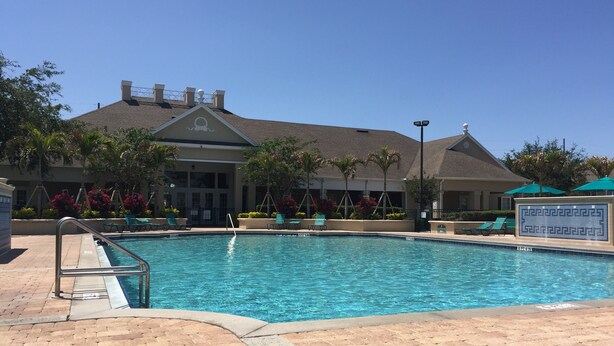 A swimming pool with a brick deck, surrounded by lounge chairs and palm trees. - 25 minutes to Disney World! Family-sized townhouse (Kissimmee)