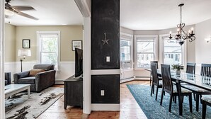 A modern living room with a sofa, coffee table, and a TV. There is a dining area with a table and chairs. - Fall In Love With Portland! (Portland)