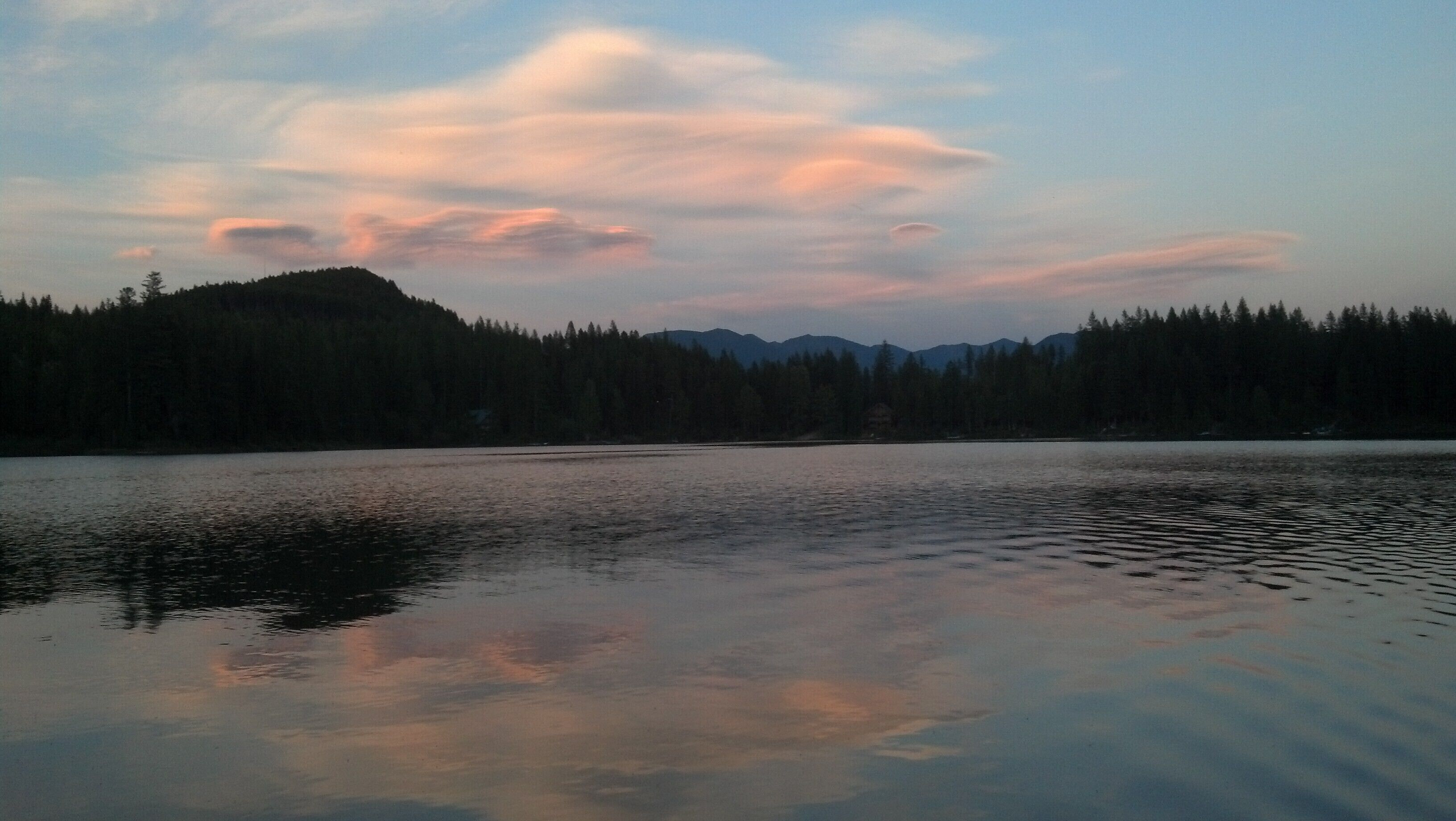 A calm lake with a forested mountain in the background.