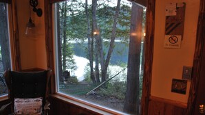 A cabin with a large window overlooking a lake and forest.