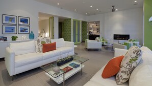A modern living room with a white sofa, a glass coffee table, and a fireplace. - Indian Wells, CA - Luxury 3 Bedroom Vacation Home (Indian Wells)
