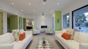 A modern living room with white sofas, a glass coffee table, and a fireplace. - Indian Wells, CA - Luxury 3 Bedroom Vacation Home (Indian Wells)