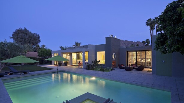 A modern house with a swimming pool, outdoor furniture, and a well-lit patio area. - Indian Wells, CA - Luxury 3 Bedroom Vacation Home (Indian Wells)