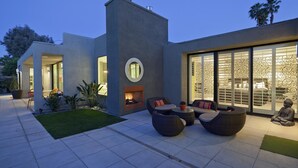 A modern house with a patio, outdoor seating, and a large sliding glass door leading to a bedroom. - Indian Wells, CA - Luxury 3 Bedroom Vacation Home (Indian Wells)