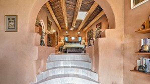 A staircase leading to a bedroom with a bed, a chandelier, and a bookshelf. - The Rass Mandal Residence:  A Unique Oasis for Families, Reunions & Getaways (Santa Fe)