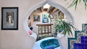 A cozy interior with a bathtub, framed artwork, and a window overlooking a garden. - The Rass Mandal Residence:  A Unique Oasis for Families, Reunions & Getaways (Santa Fe)
