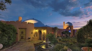 A courtyard with a fountain, stone pathway, and a building with arched doorways and domed roofs. - The Rass Mandal Residence:  A Unique Oasis for Families, Reunions & Getaways (Santa Fe)