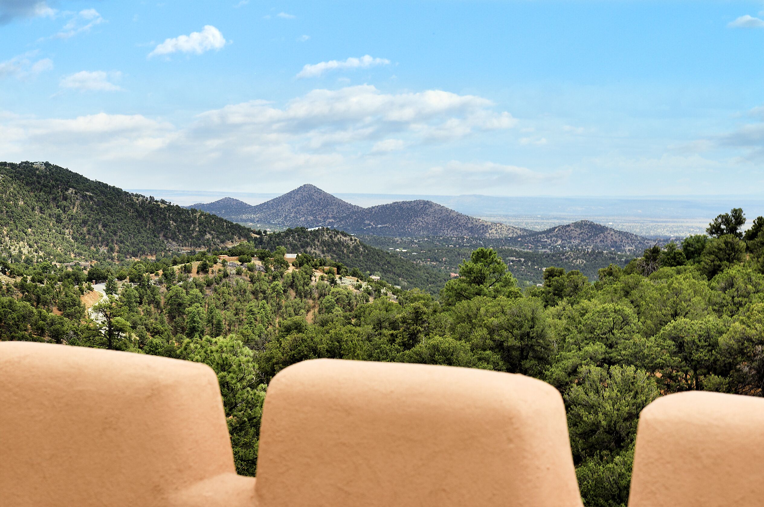 Vista desde un punto elevado sobre un paisaje montañoso con bosques densos y edificios dispersos.