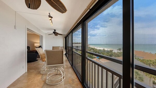 A balcony with a view of the ocean, a ceiling fan, and a chair.