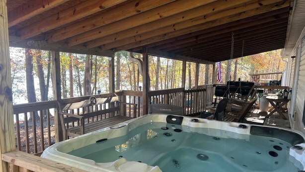 A hot tub under a wooden deck with a view of trees and a grill area. - 15 PRIVATE ACRES !! WATERFRONT, SWIMMING POOL !! HOT TUB !!  PETS WELCOME TOO !! (RICHFIELD)
