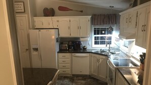 A kitchen with white cabinets, a refrigerator, a dishwasher, a coffee maker, and a window with curtains. - 15 PRIVATE ACRES !! WATERFRONT, SWIMMING POOL !! HOT TUB !!  PETS WELCOME TOO !! (RICHFIELD)