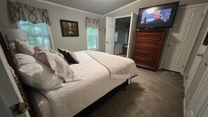A bedroom with a bed, a TV, a dresser, and a door leading to another room. - 15 PRIVATE ACRES !! WATERFRONT, SWIMMING POOL !! HOT TUB !!  PETS WELCOME TOO !! (RICHFIELD)