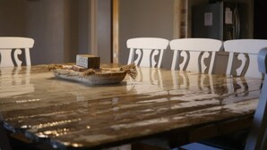 Una mesa de comedor de estilo rústico, rodeada de sillas blancas.