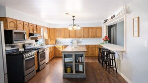 Una cocina moderna con armarios de madera, electrodomésticos de acero inoxidable y una isla central con taburetes.