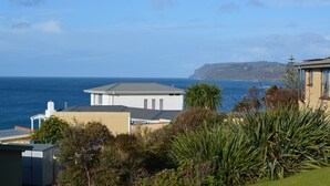 Ein Küstenwohngebiet mit einem weißen Haus und einem gelben Gebäude, umgeben von Grün und mit Blick aufs Meer.