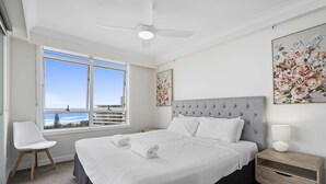 Ein Schlafzimmer mit einem großen Bett, einem Nachttisch, einem Sessel, einem Deckenventilator und einem Fenster mit Blick.