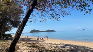 Une plage animée, un ciel dégagé et une île lointaine.