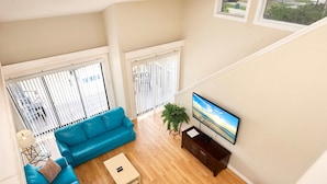 Una sala de estar con un sofá azul, una mesa de centro y un televisor sobre un mueble de madera.