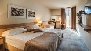 Habitació d'hotel amb un llit gran, una taula de treball, una cadira i dues fotografies emmarcades a la paret.