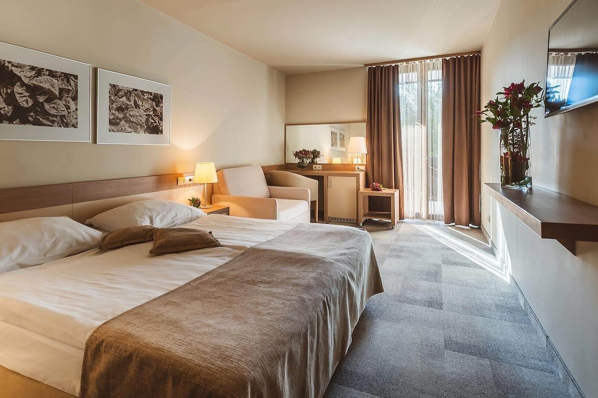 Habitación de hotel con una cama grande, un escritorio, una silla y dos cuadros en la pared.