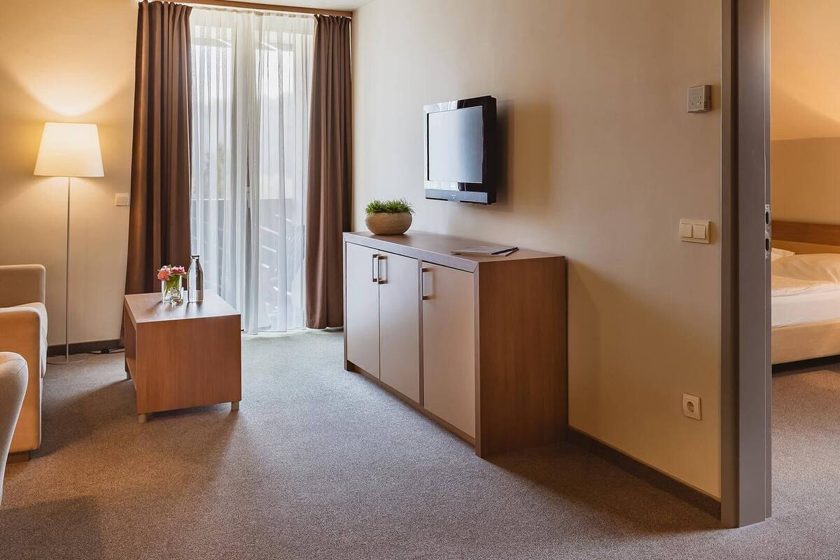 Habitación de hotel con cama, escritorio, televisión y vistas al exterior.