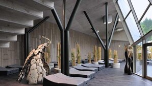 Ein modernes Interieur mit einzigartigem architektonischen Design, das eine große Felsformation, gemütliche Sitzbereiche und einen Ausblick durch große Fenster zeigt.