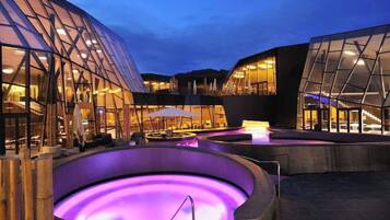 A modern building with glass facades and a heated outdoor pool area.