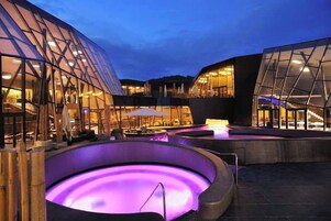 Un edificio moderno con fachadas de vidrio y un área de piscina exterior climatizada.