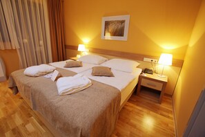 A hotel room with a large bed, two bedside tables, a nightstand, and a wall-mounted lamp. - Hotel Breza (Podcetrtek)