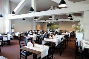 A spacious restaurant with multiple tables and chairs, pendant lighting, and a neutral color scheme. - Hotel Breza (Podcetrtek)