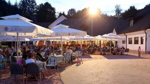 Ein Straßencafé mit mehreren weißen Sonnenschirmen und Tischen, umgeben von Pflasterwegen und Gebäuden.