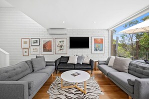 Ein modernes Wohnzimmer mit grauen Sofas, einem runden Couchtisch und Kunstwerken an der weißen Ziegelwand.