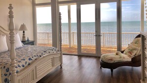 A bedroom with a bed, a nightstand, a chair, and a view of the sea through large glass doors. - Beach Dream House, relax and enjoy the clear waters of Islamorada  FL  (Islamorada)