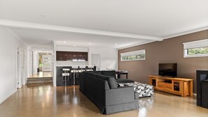 Ein geräumiger Wohnbereich mit einem schwarzen Ecksofa, einer Holzeinrichtung und einem Fernseher.