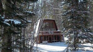 Una cabana amb un balcó, envoltada d'arbres coberts de neu.