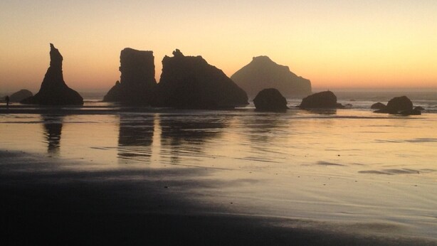 A beach with rock formations at sunset.
